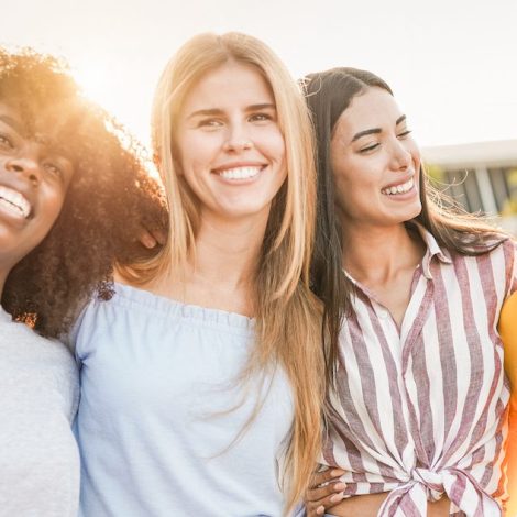Happy multiracial friends in the city - Four women with different skin color hugging each other outdoor